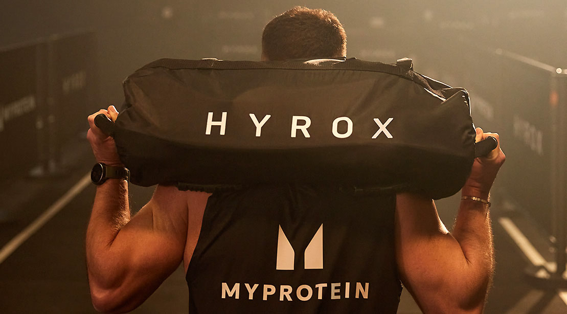 Man carring a weighted Hyrox bag over his shoulder